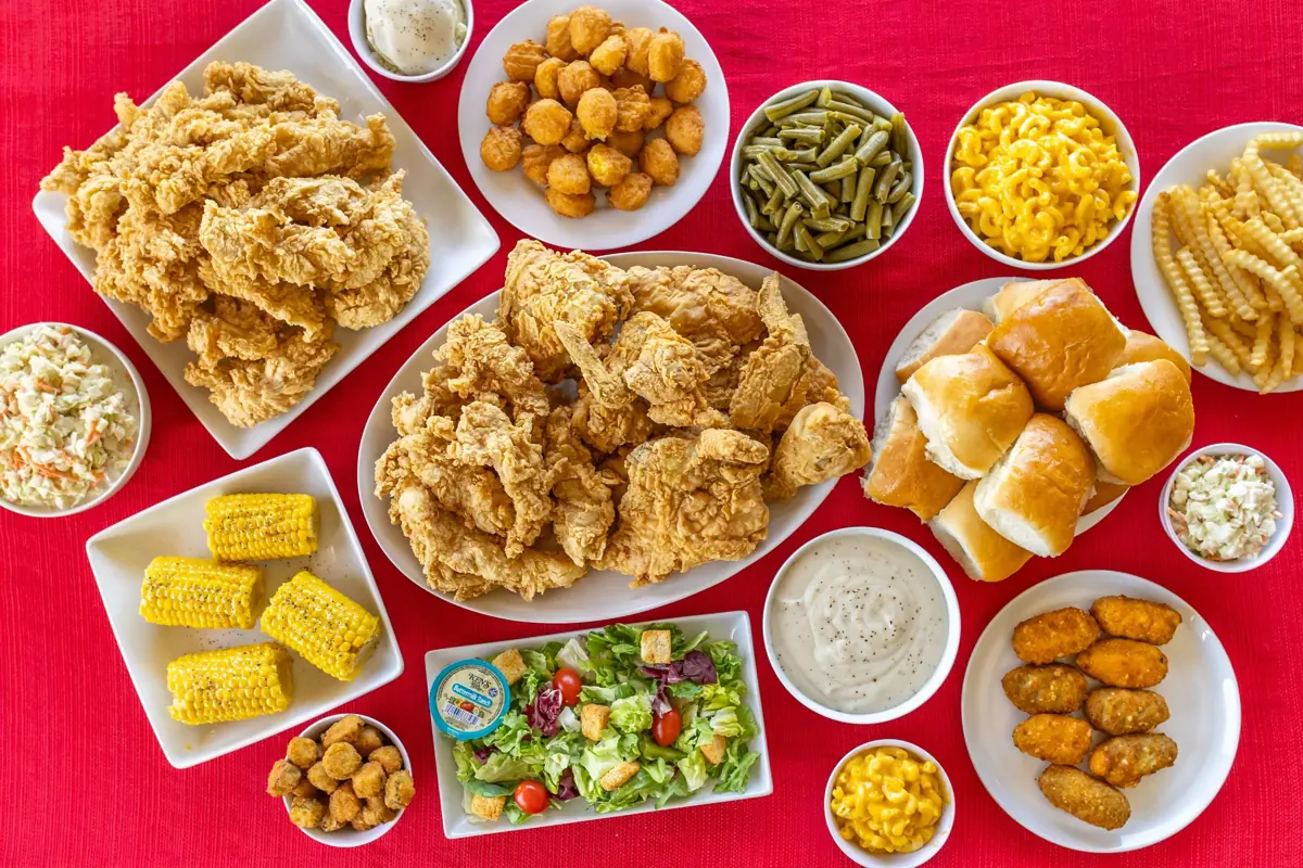 Bush’s Chicken tenders, fried chicken, rolls, gravy and sides spread on a red table